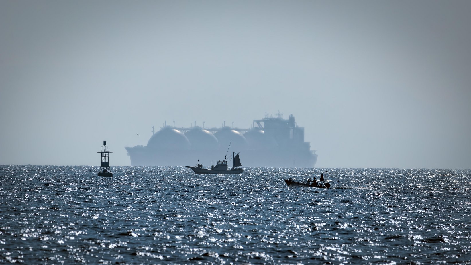 Two fishing boats being over shadowed by a Liquid Natural Gas tanker (LNG) in Japan?s Tokyo Bay.