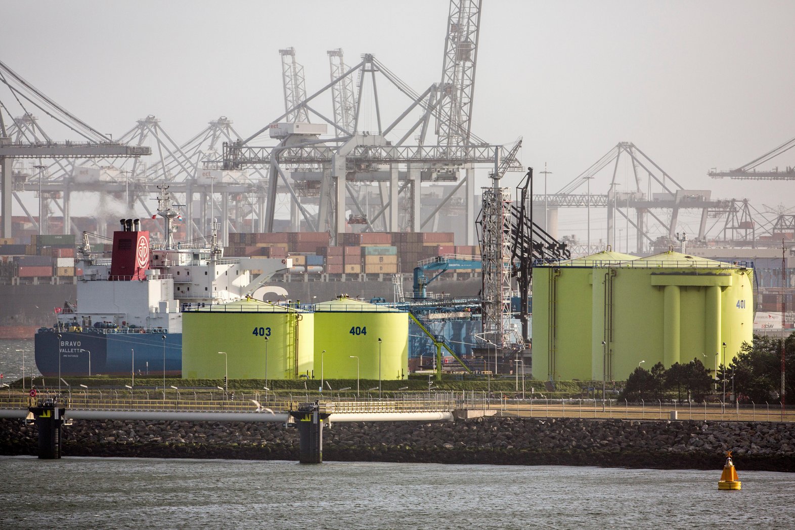 Netherlands, Rotterdam, Port of Rotterdam. Container harbour or harbor. Foreground LNG, liquid natural gas storage